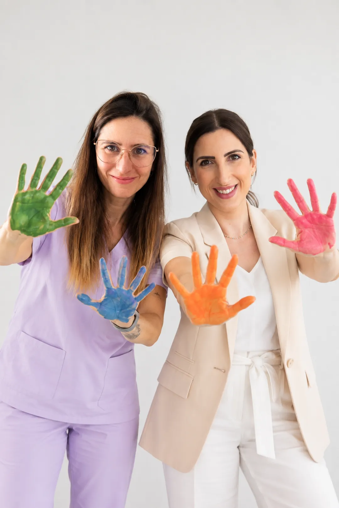 Sandra i Ani, l'equip d'Espai Tribu a Vilanova i la Geltrú, mostren les mans pintades de colors.