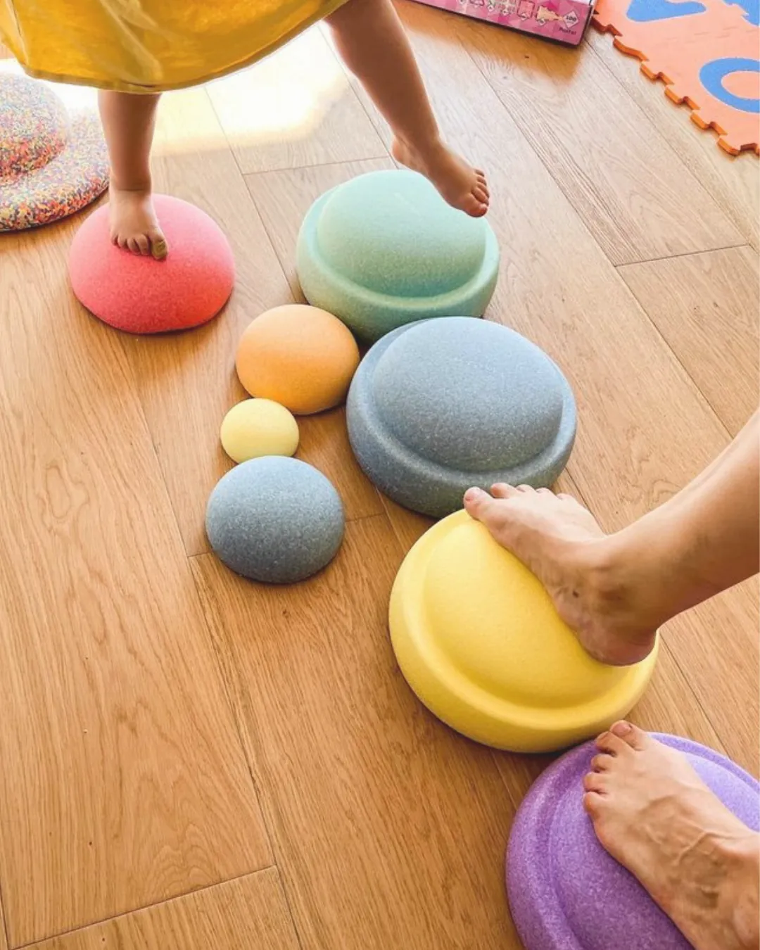 Peus d'un infant sobre pedres d'equilibri de colors, amb boles de fusta.