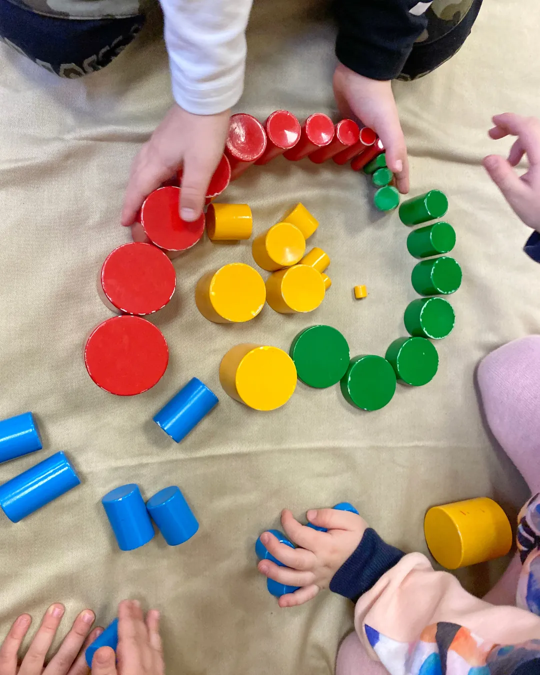 Mans d'infants classificant peces i taps de colors per grups.